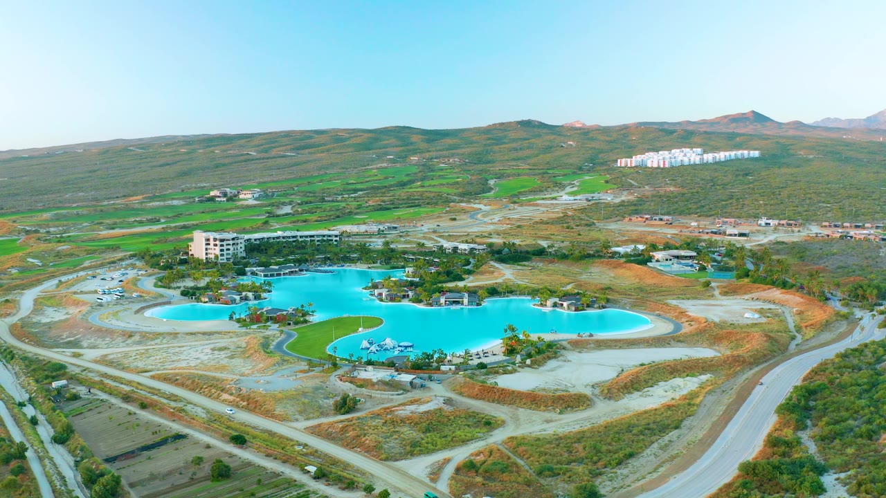 Aerial reservoir scene with a road network and hilly open terrain beyond.