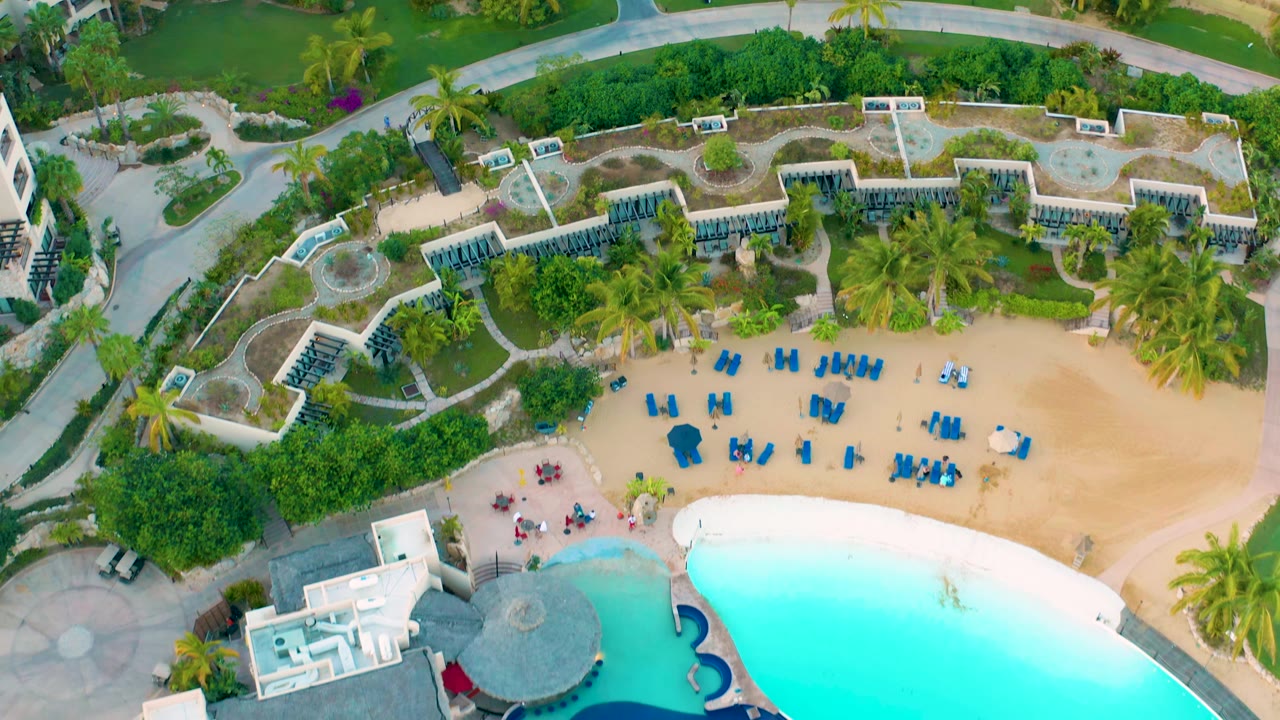 Aerial view of resort pool, palms, and rows of blue chairs