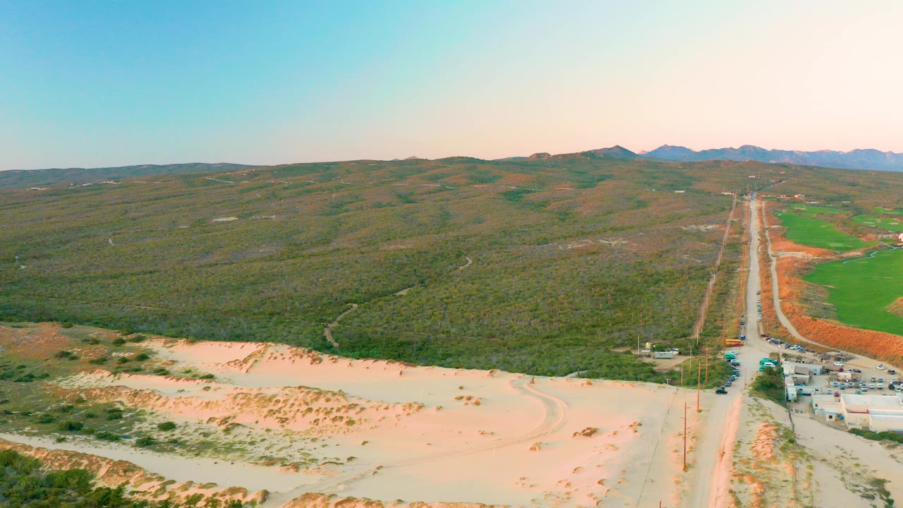 Aerial view of a straight rural road through sandy and hilly terrain.