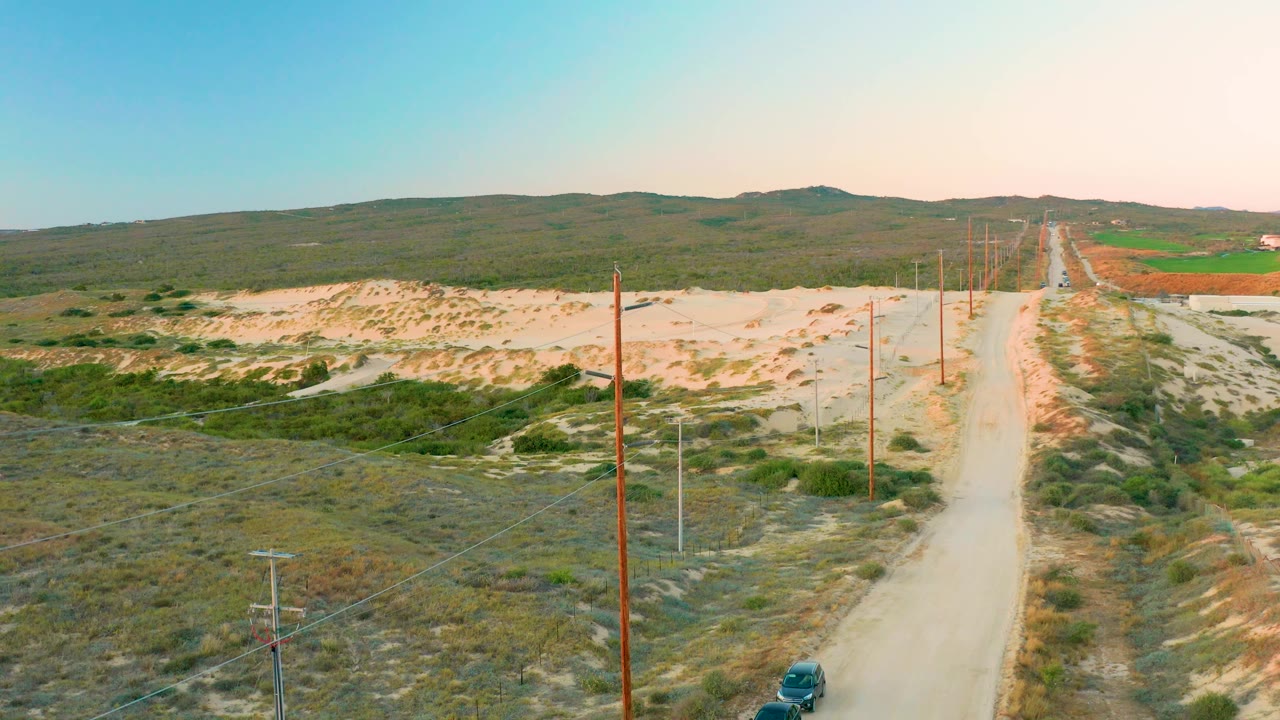 Aerial road view with a dark vehicle beginning to appear near the lower edge.