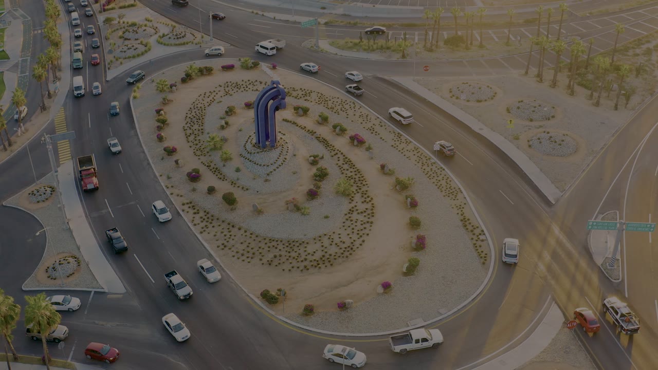 Aerial traffic view with cars entering and exiting a landscaped roundabout.