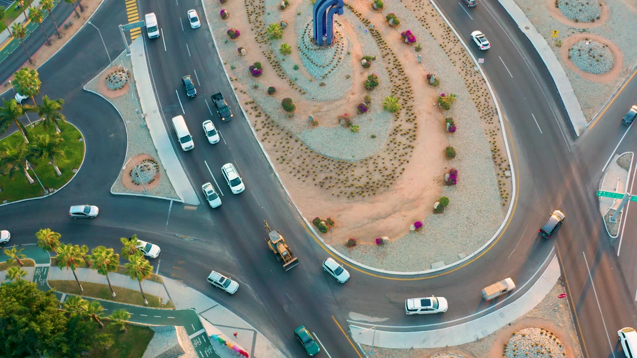 Top-down roadway view with traffic around a planted circle.