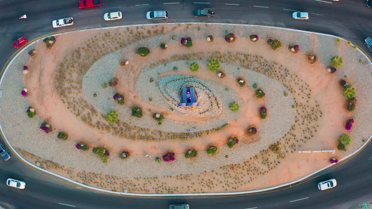 Top-down view of a spiral-landscaped roundabout in San Jose del Cabo, Baja California Sur, with cars on the surrounding lanes and no visible people.