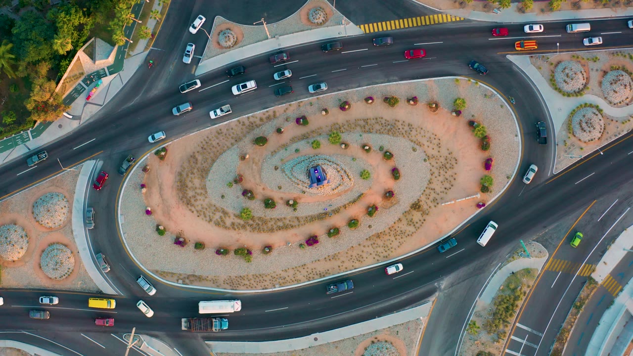 Overhead shot of a landscaped traffic circle with cars and buses.
