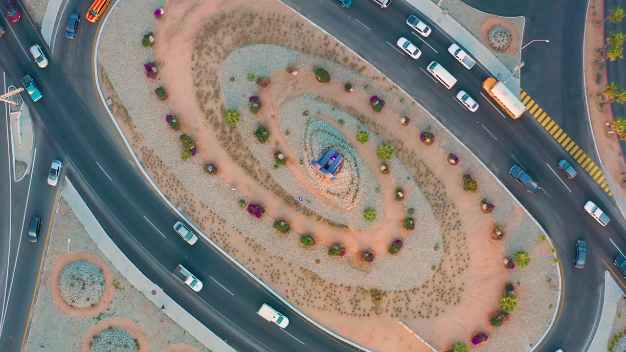 Aerial traffic beside a gravel and flower roundabout