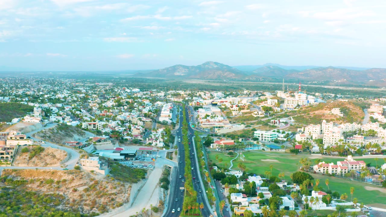Aerial view of a city highway with traffic and a curved road below dry hills.