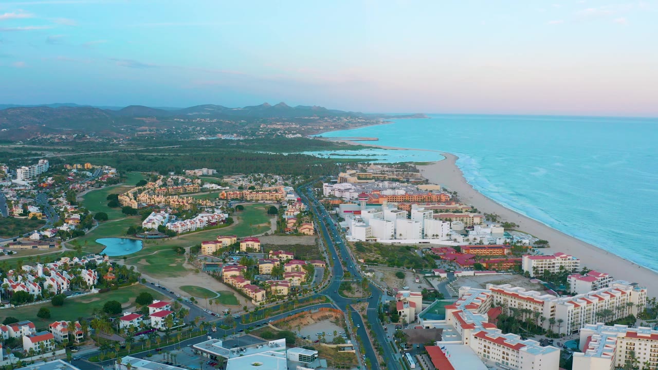 Aerial view of coastal town, beach, ocean, roads, and green spaces.