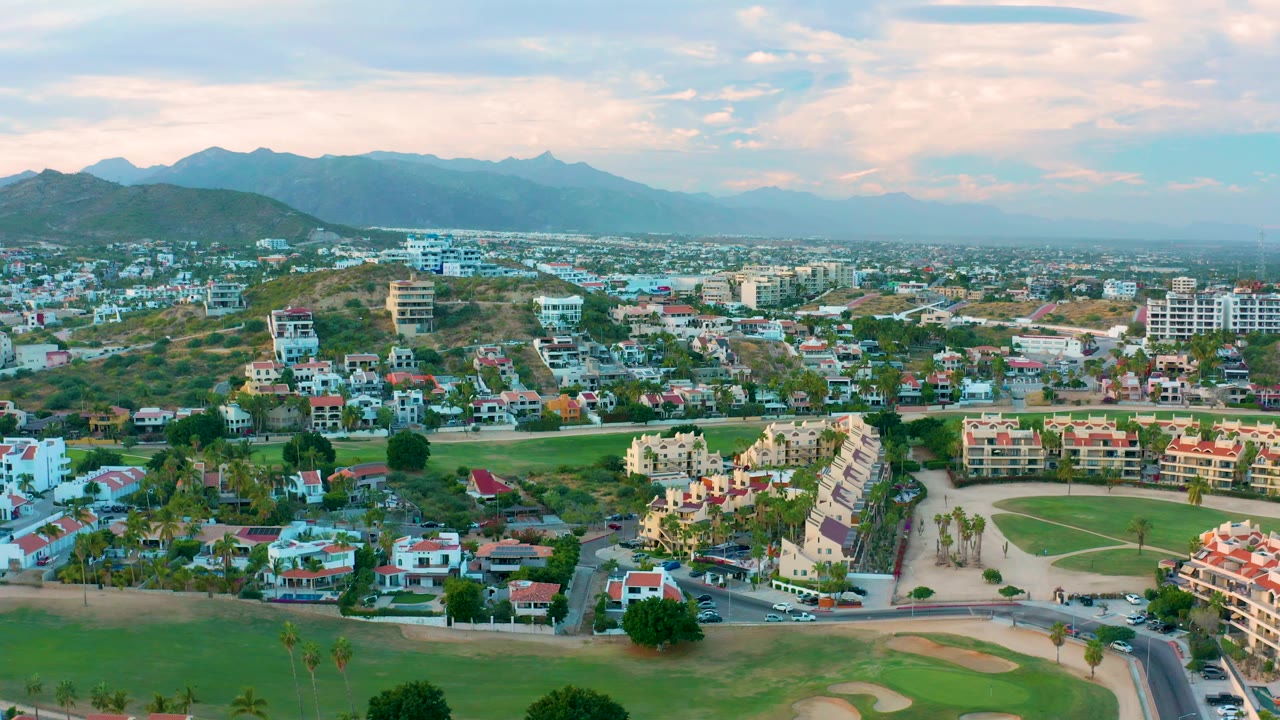 Aerial neighborhood panorama with golf course foreground and mountains in back.