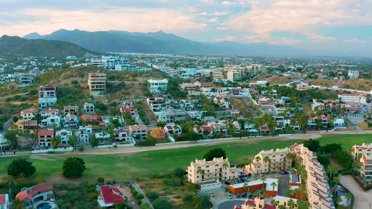 Residential blocks beside open green space with mountains behind