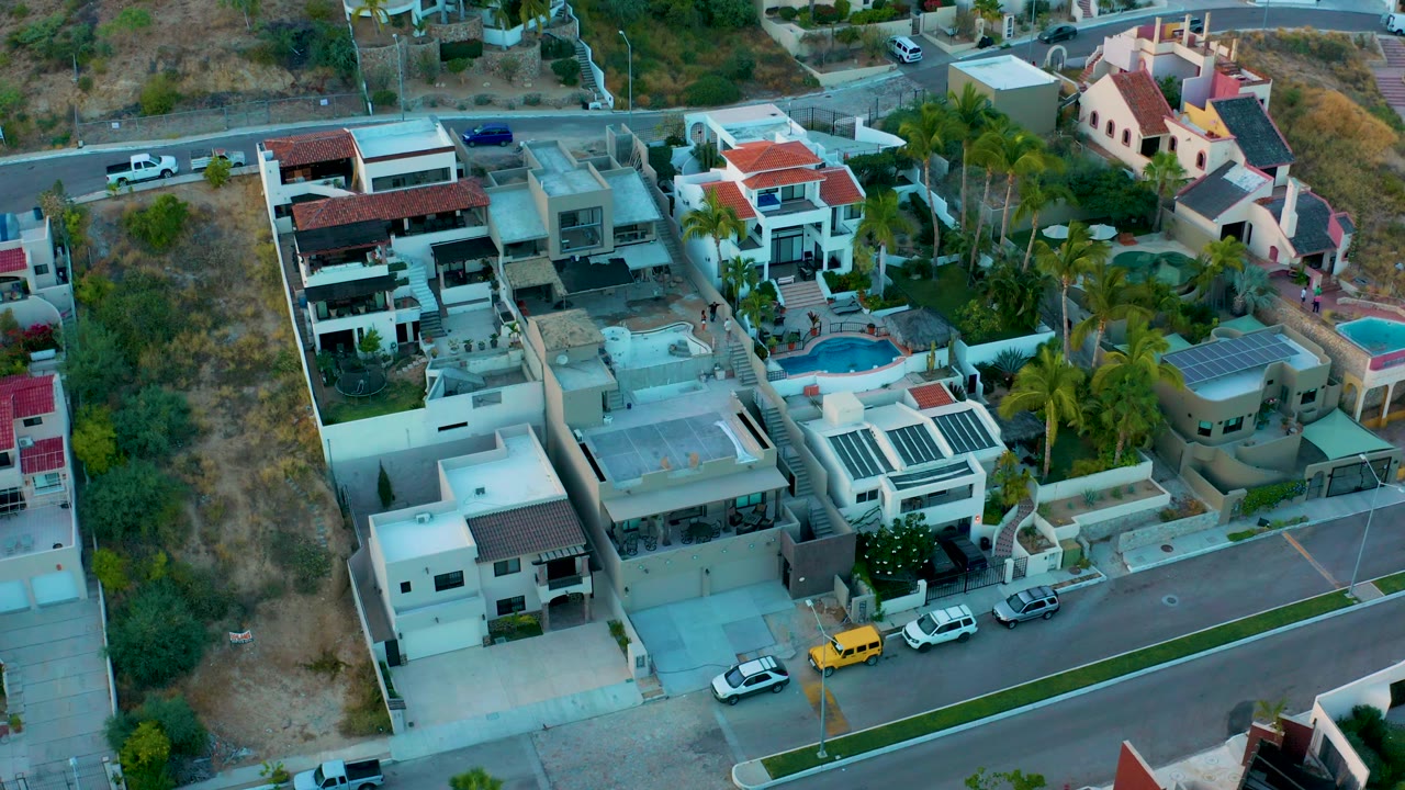 Aerial angle over modern houses, a blue pool, and palm-lined yards.