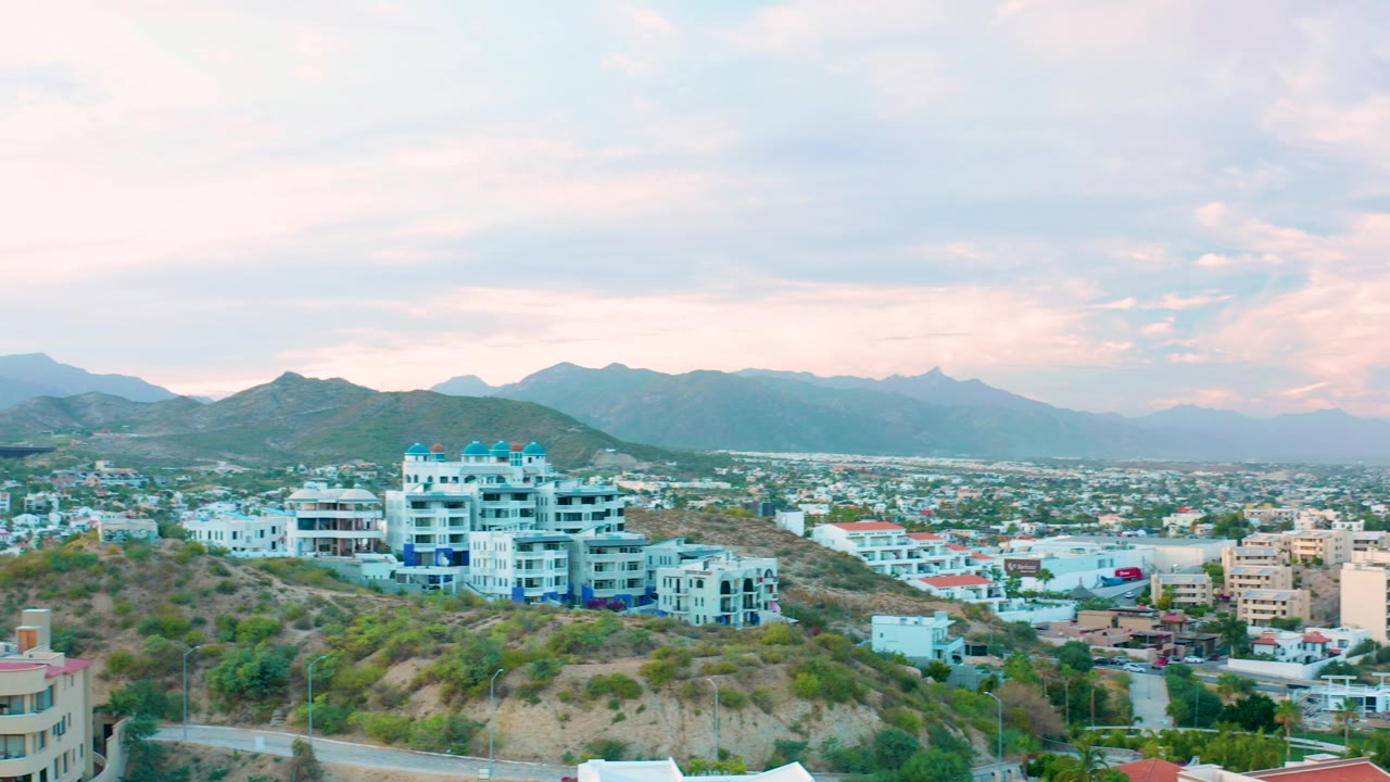 Hillside neighborhood overlooking city buildings and distant mountain ridges.