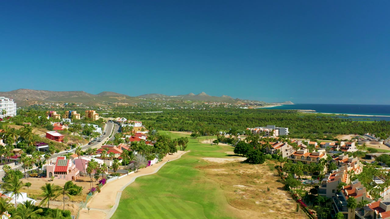 Aerial neighborhood view beside a golf course and coastal tree line