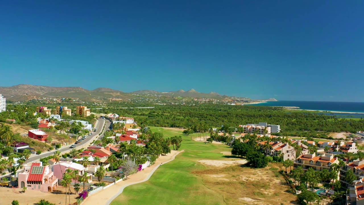 Aerial road view beside green golf course and coastal homes
