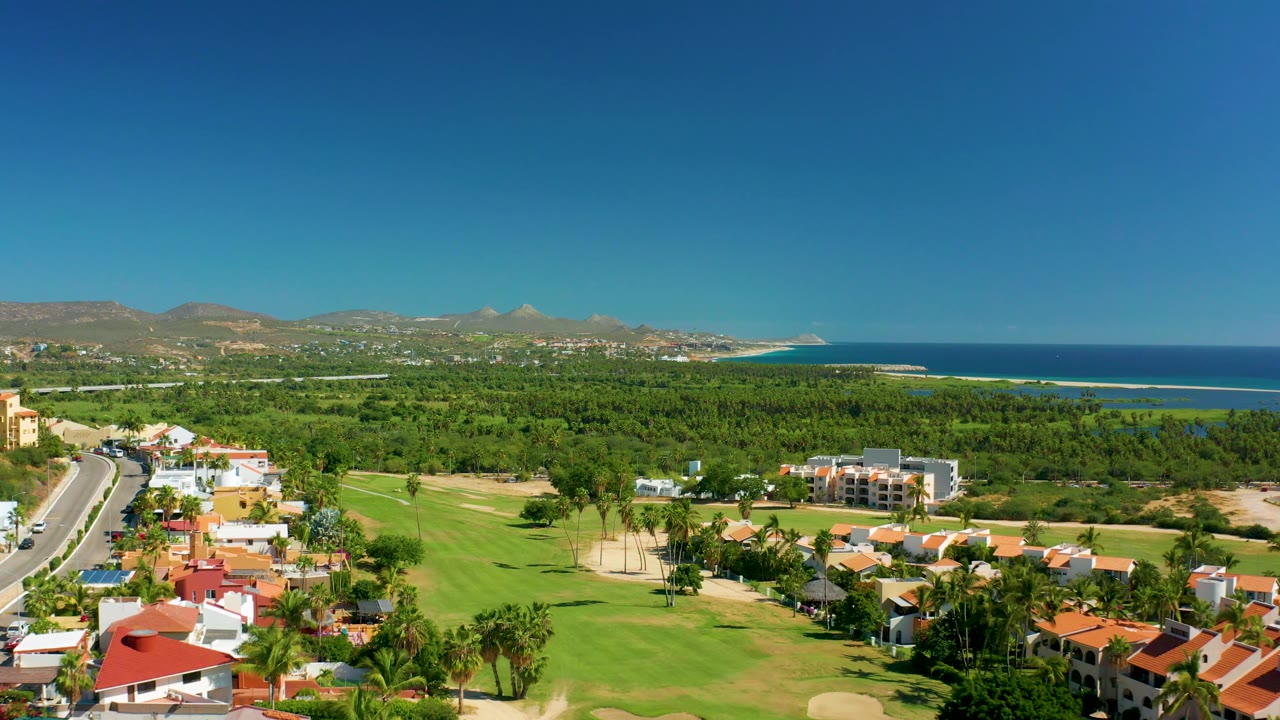 Drone view of road beside golf course and coastal greenery