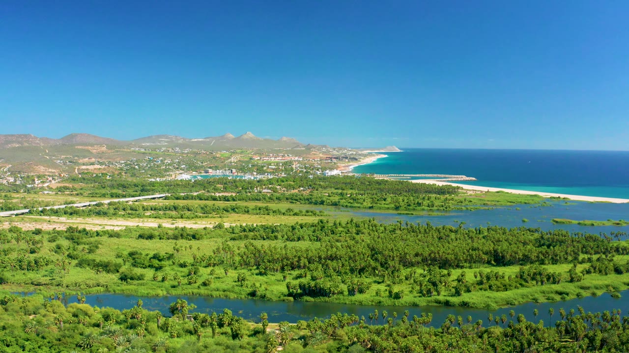 River and green fields stretch toward the coast with mountains and ocean in the background.