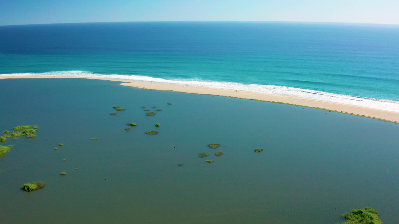 Aerial view of lagoon, sandbar, and turquoise ocean surf.