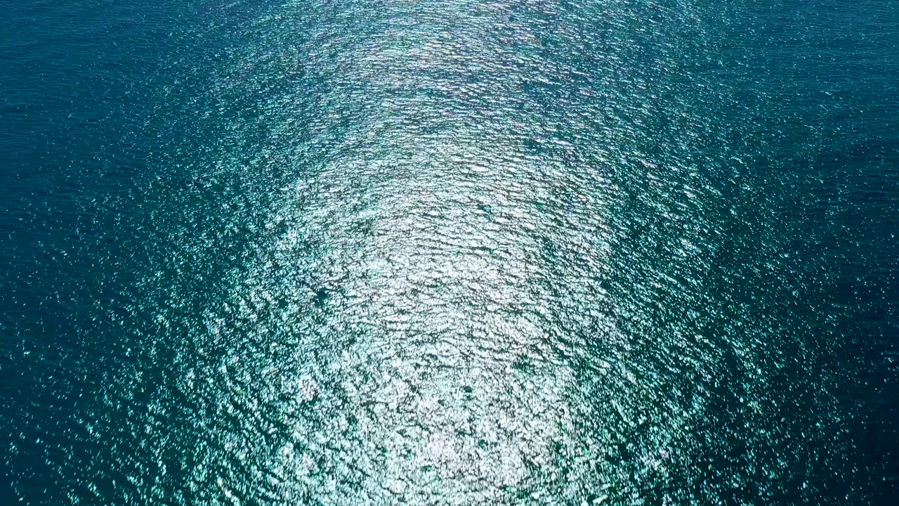 Blue and teal ocean surface in San Jose del Cabo with a dense white reflection spreading across small ripples, no visible people.