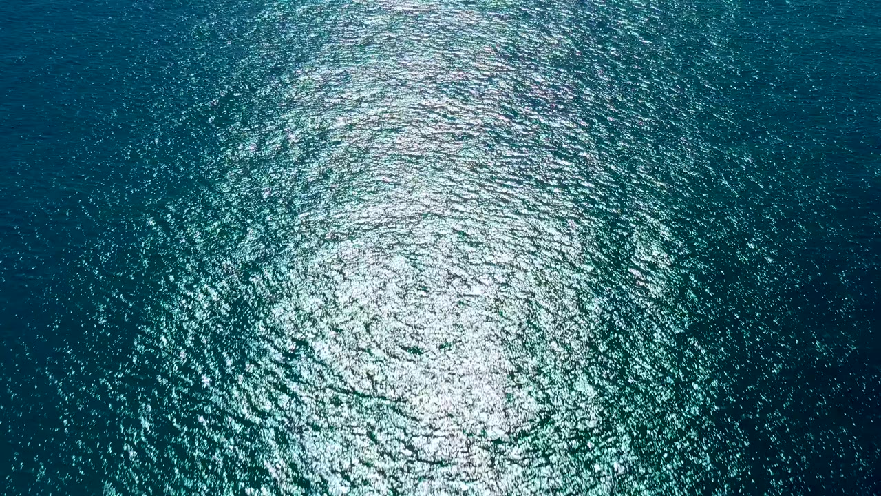 Rippled ocean surface with bright reflection low in the frame.