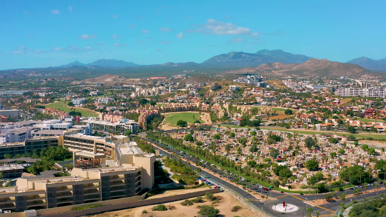 Aerial suburban scene with foreground building, neighborhood streets, trees, and mountain skyline.