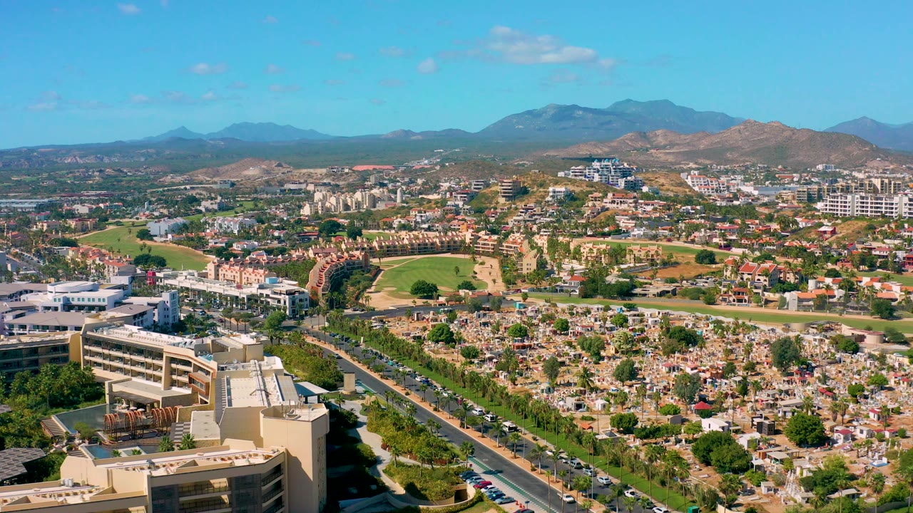 Aerial cityscape with a road, parking areas, homes, and mountains