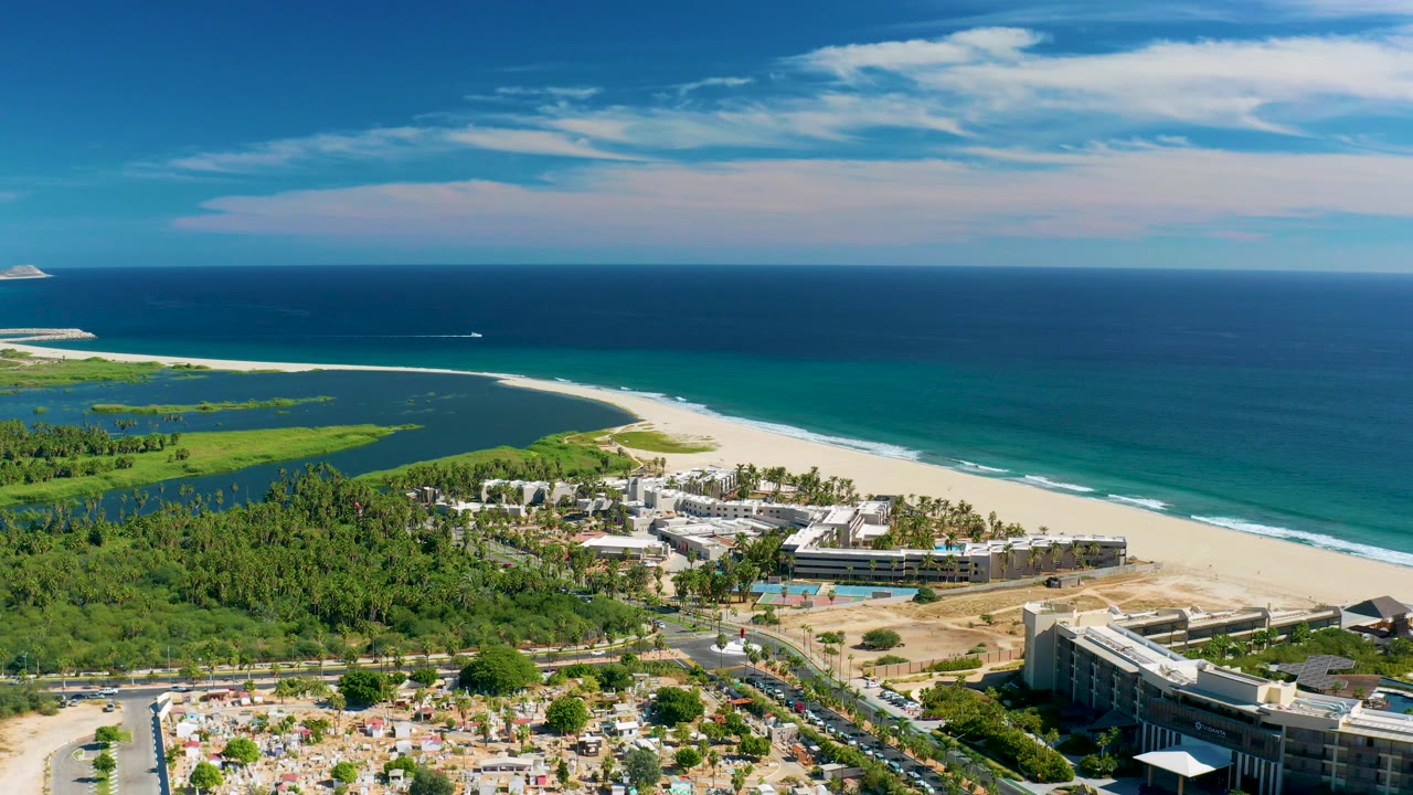 Aerial beach resort view with greenery, ocean, and distant boat
