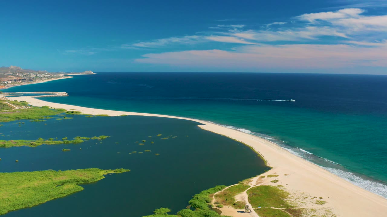 Sandy shoreline curves past calm lagoon toward open ocean