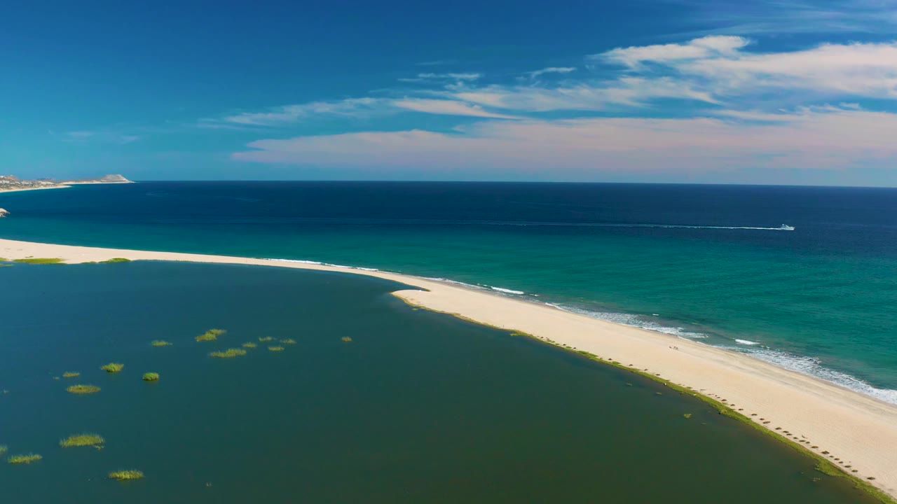 San Jose Del Cabo aerial view with the sandbar curving across the frame, lagoon water in the foreground, ocean beyond it, and no visible people.