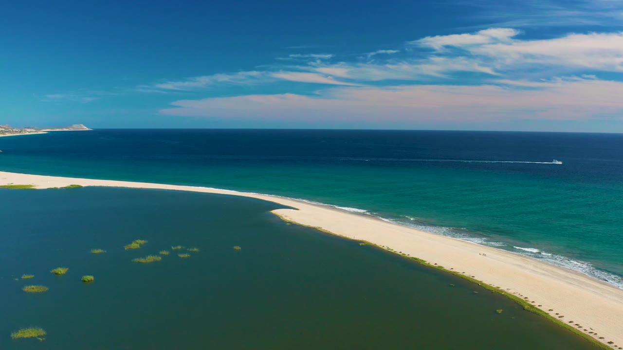 San Jose Del Cabo aerial frame with the lagoon filling more of the lower view, the sand spit running diagonally, ocean surf on the far side, and no visible people.