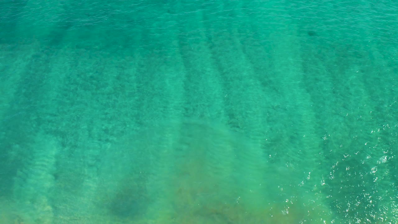 Overhead turquoise ocean water with darker seabed patches.