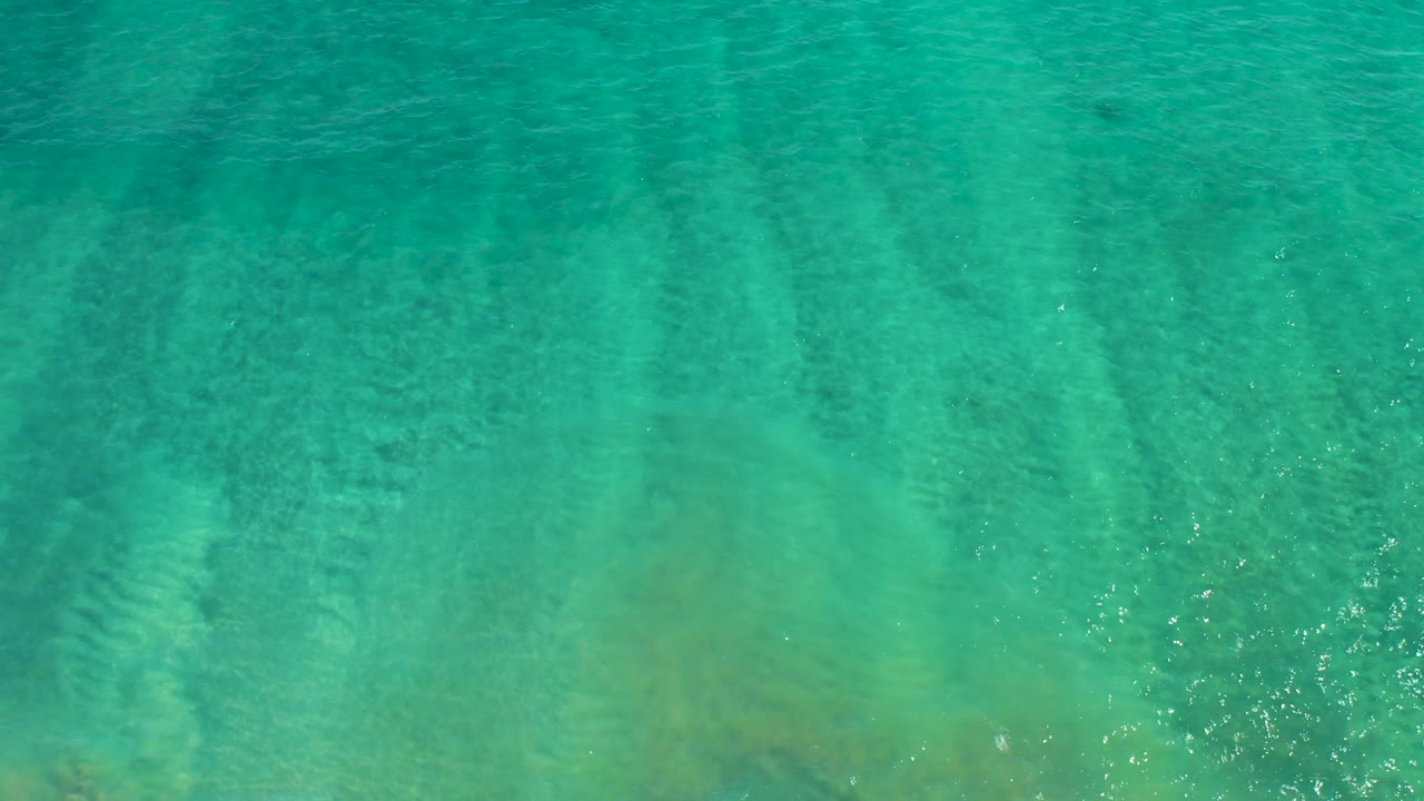 Turquoise water in San Jose del Cabo shows stronger shallow color variation and submerged seabed forms, with no visible people.