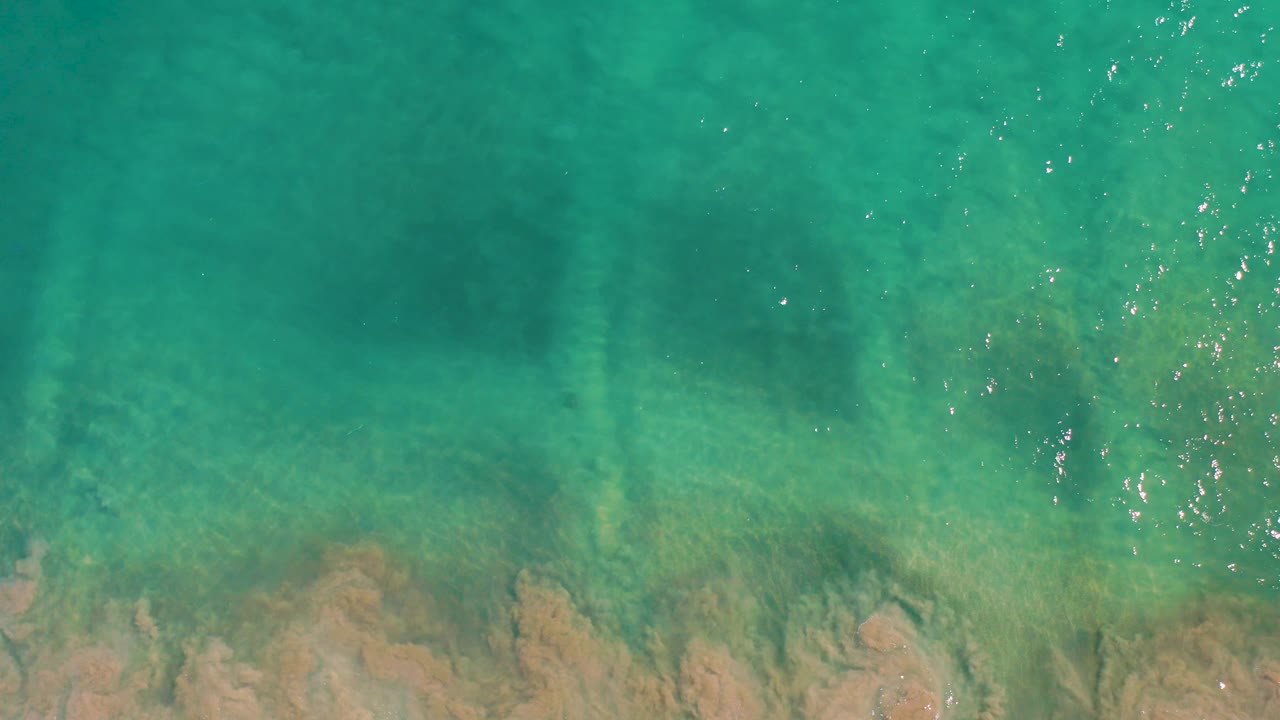 Aerial-looking view of shallow San Jose del Cabo ocean water, with darker bands beneath the surface and no visible people.