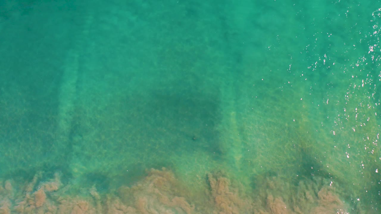 Rippling turquoise water covers a pale rocky bottom in San Jose Del Cabo, with the frame kept entirely on the water surface and no visible people.