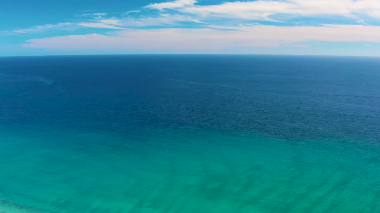 Turquoise shallows below dark blue ocean and clouds