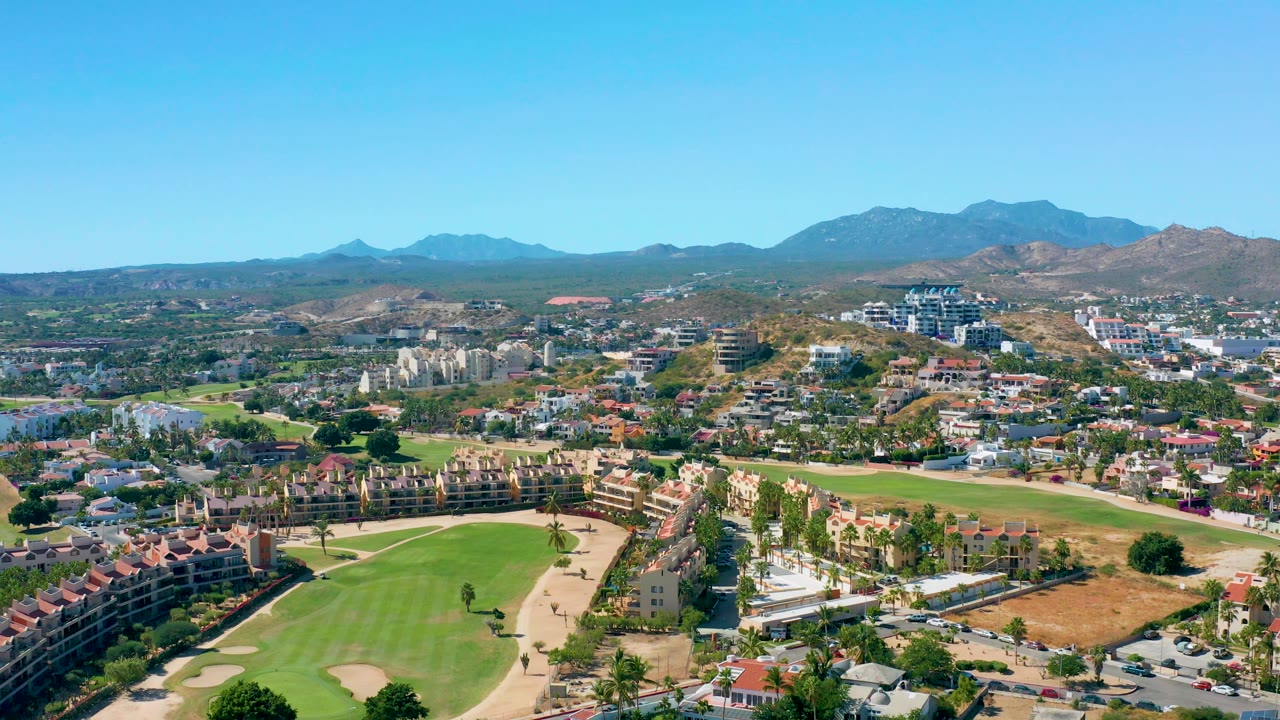 Aerial panorama of homes and a golf course with mountains on the horizon.