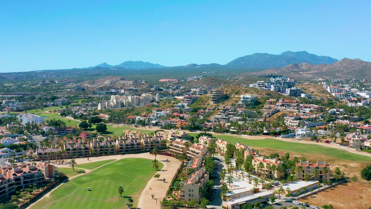 Aerial landscape of golf fairway, homes, roads, and distant mountains.