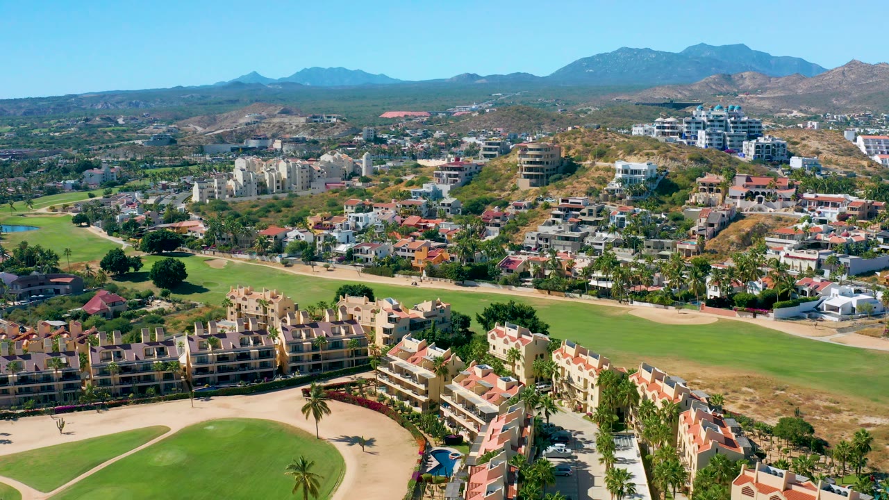 Aerial view across golf course, condos, houses, hills, and mountains.