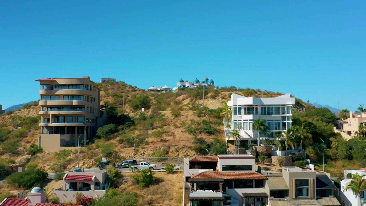 Dry hillside with residential buildings and clear sky.
