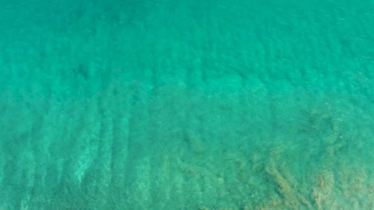 Turquoise shallow ocean water over sandy bottom.