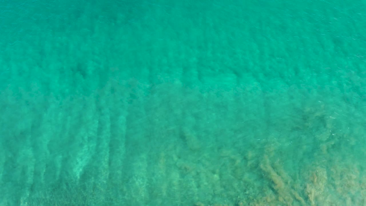 Clear San Jose Del Cabo ocean water fills the frame as narrow ripple bands drift across the sandy bottom, with no visible people.