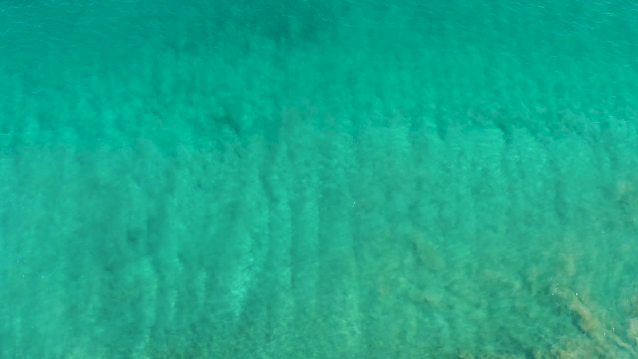 Clear blue-green ocean water in San Jose Del Cabo shows refracted light bands crossing the sand below, with no visible people or objects.