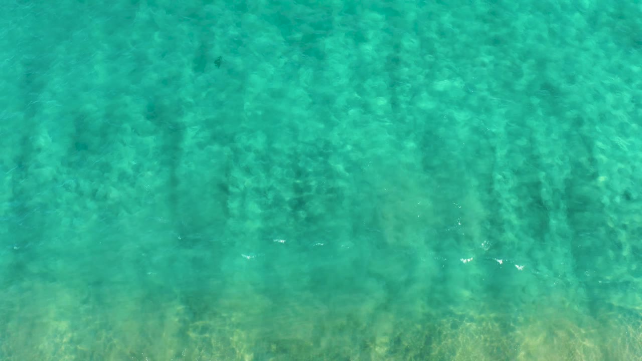 Clear blue-green water in San Jose del Cabo fills the frame, with rippled sunlight over the seabed and no visible people.