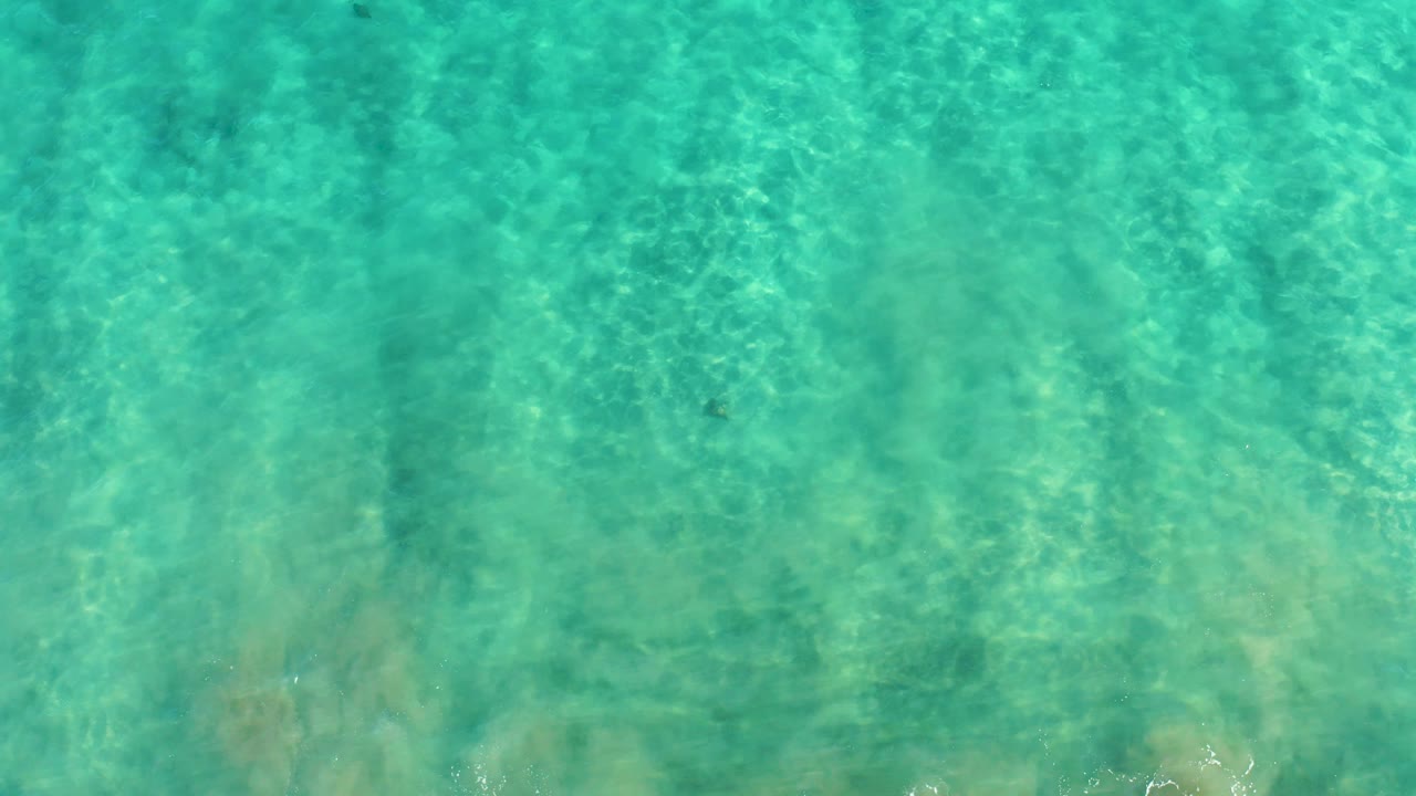 An overhead aqua water frame from San Jose Del Cabo shows the seabed through ripples, with slightly darker underwater areas and no visible people.