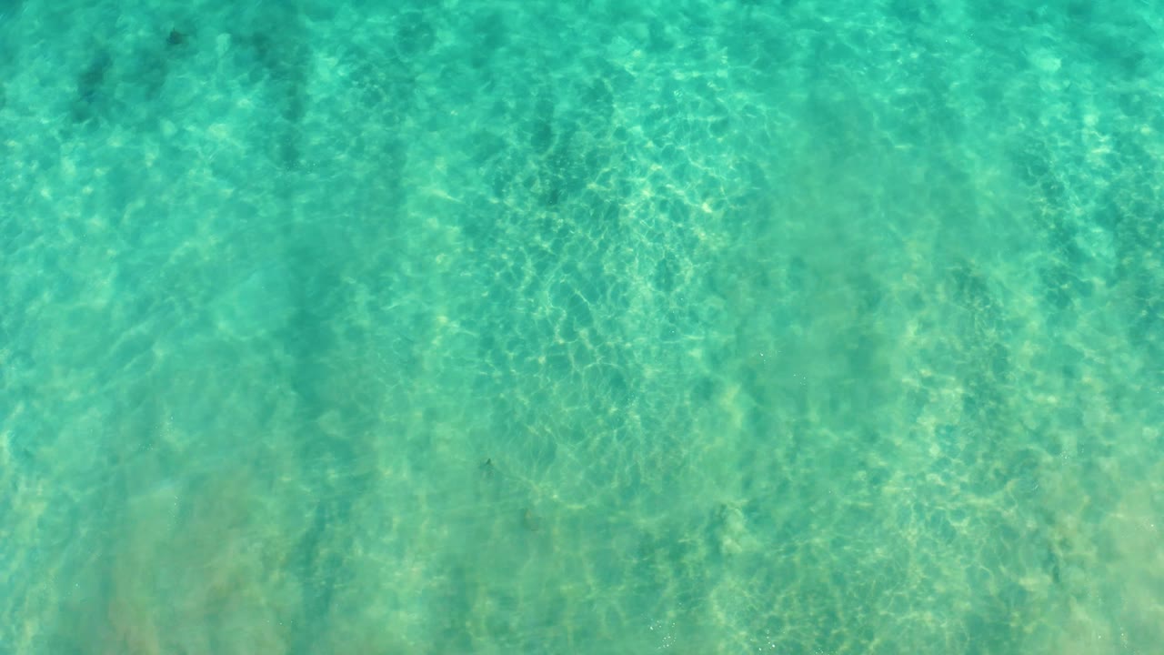 Shallow turquoise ocean water in San Jose del Cabo shows bright sunlit ripple patterns across the seabed with no visible people.
