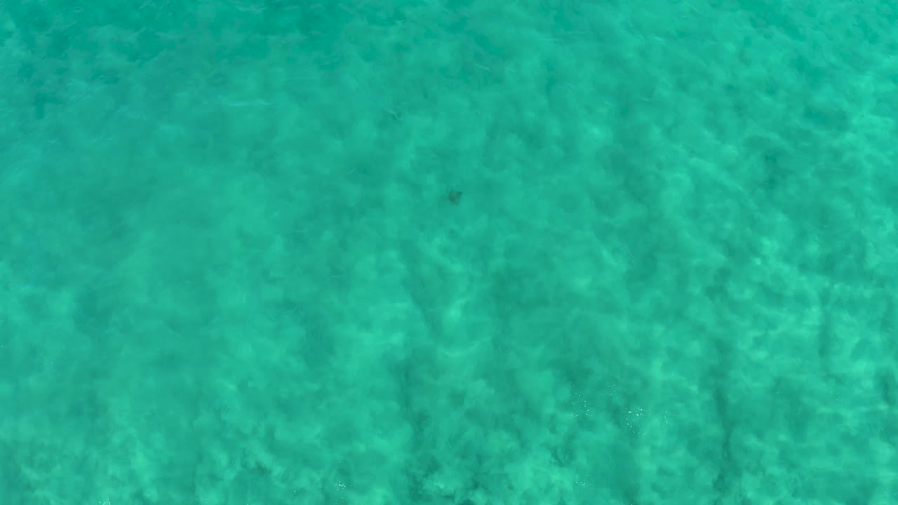 Turquoise water with subtle darker patches below the surface.
