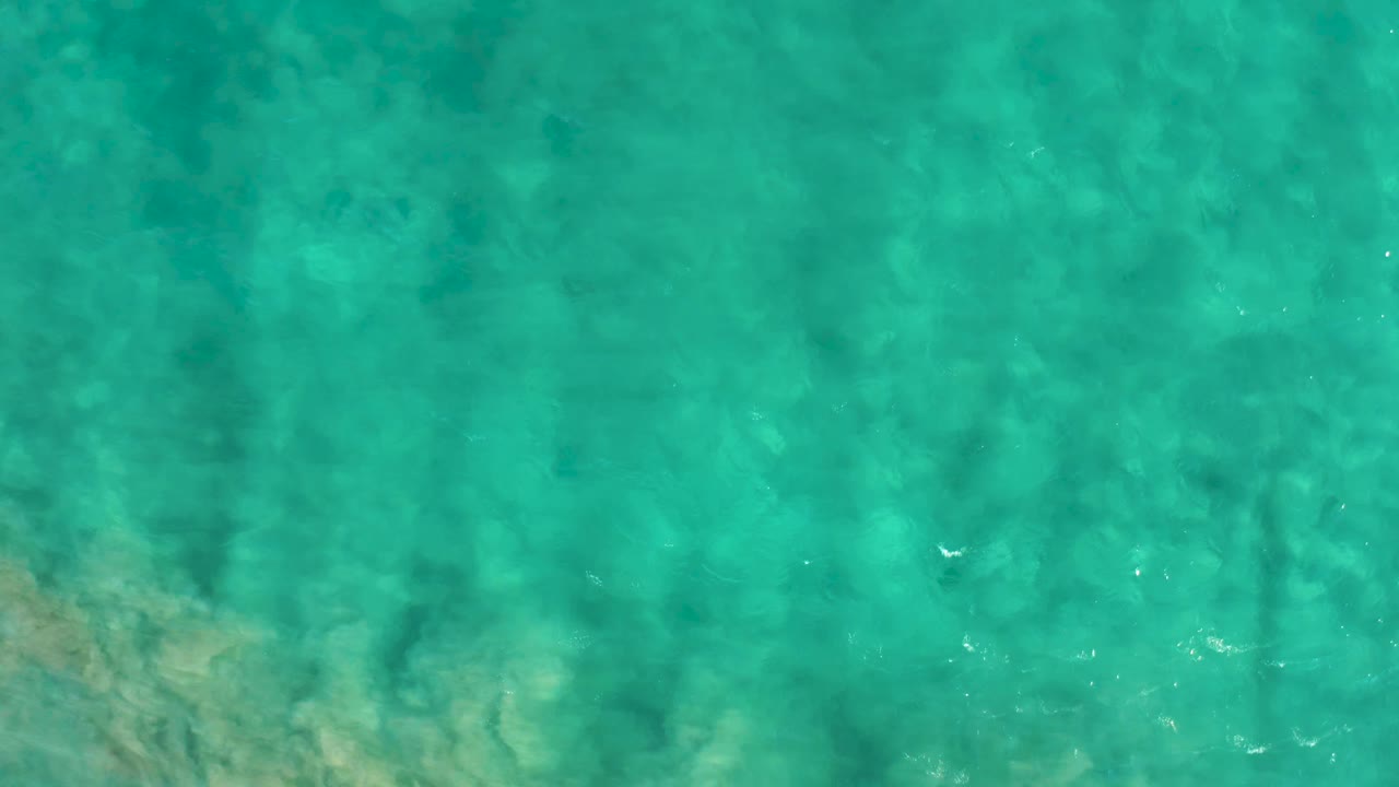 Top-down view of shallow turquoise water in San Jose Del Cabo with a faint sandy bottom and no visible people.