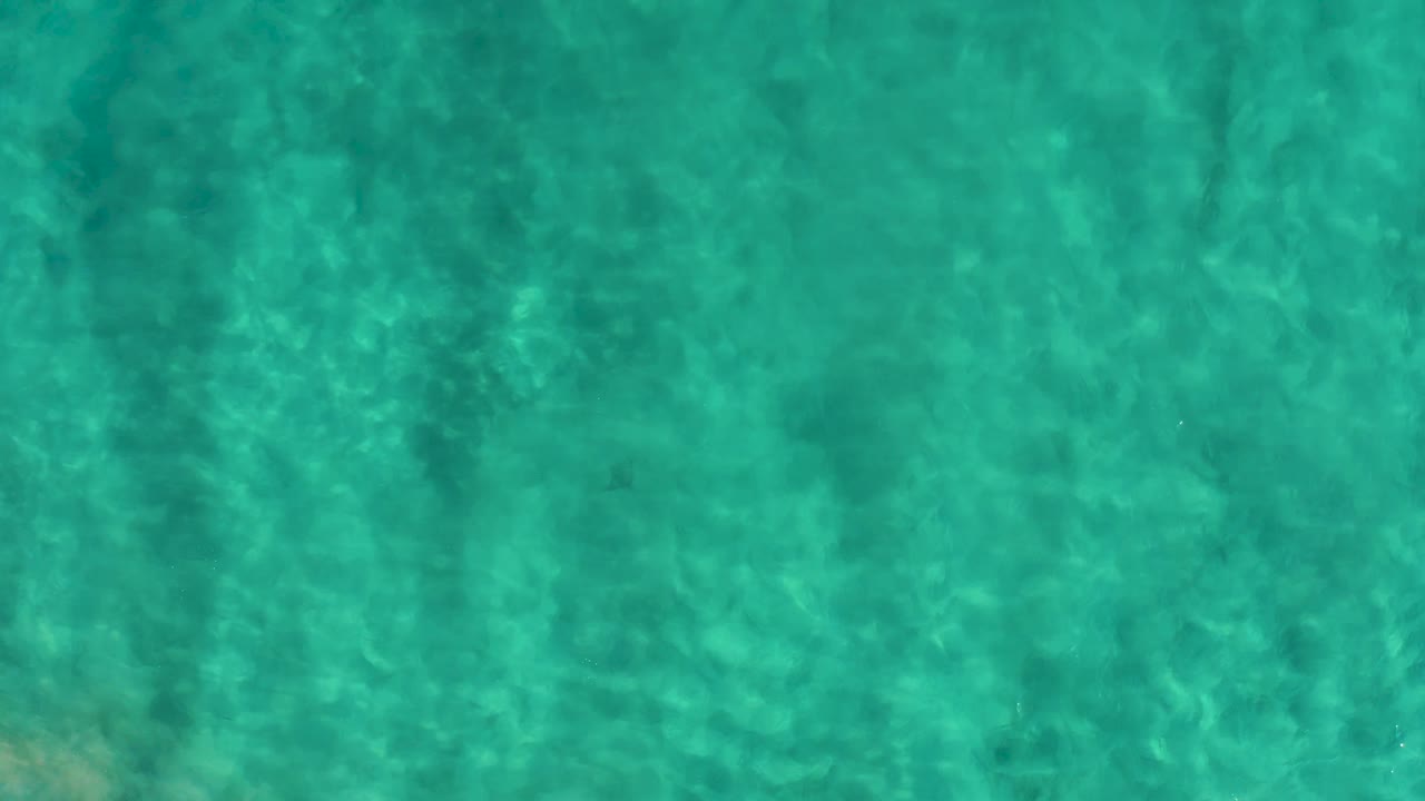Turquoise shallow water in San Jose del Cabo fills the frame with the bottom visible, pale underwater patches, and no visible people.