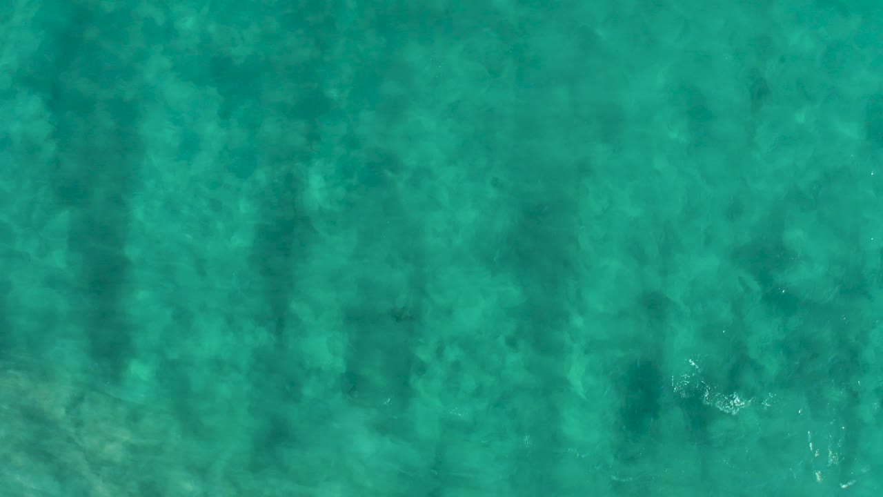 Turquoise sea surface in San Jose Del Cabo fills the frame with soft shadow columns and faint bottom detail, with no visible people, vessels, or shoreline.