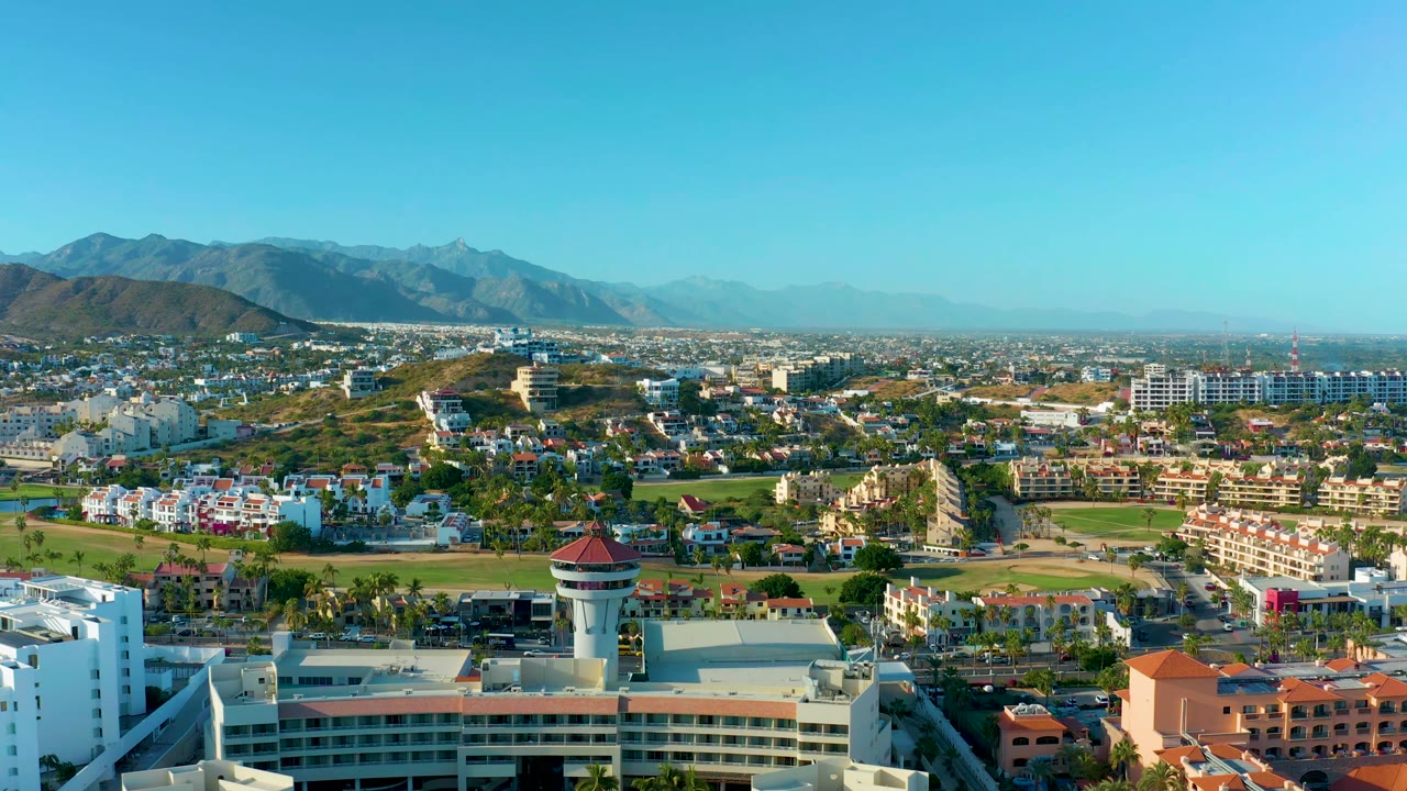 Wide aerial view of buildings, green space, and mountains