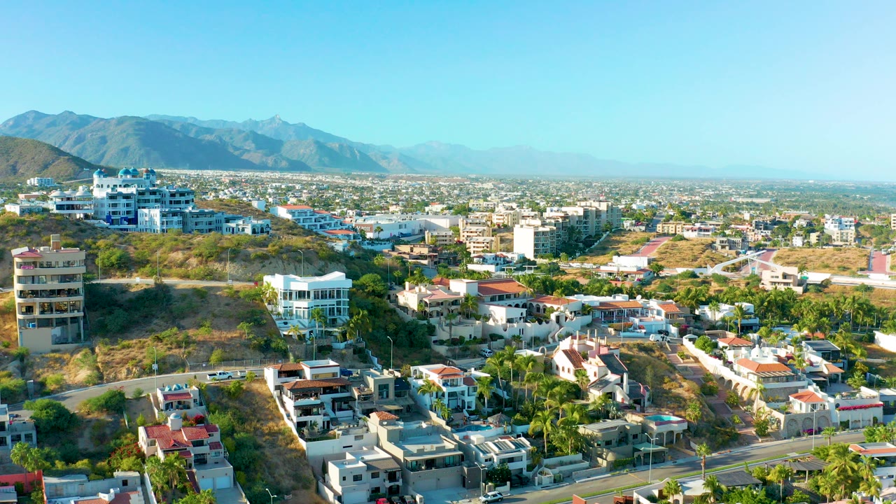 Aerial view of hillside homes, roads, palms, and distant mountains in San Jose del Cabo, with no visible people.