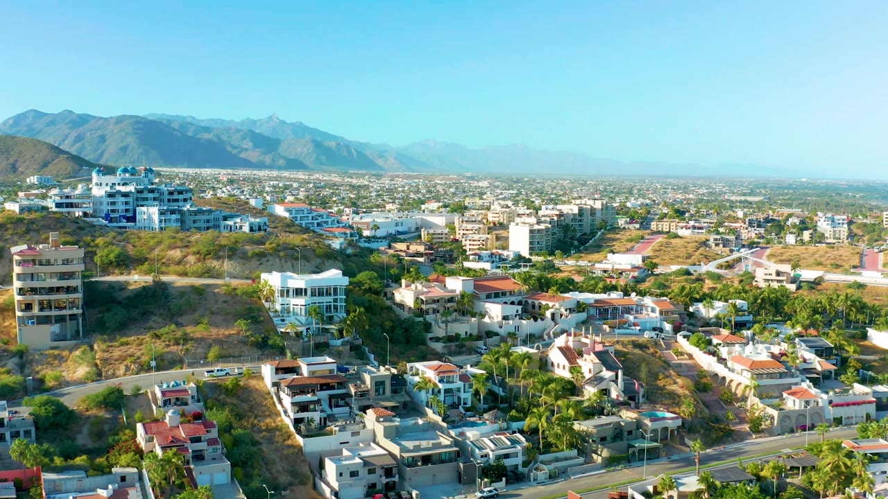 Residential hillside with white buildings and mountain horizon